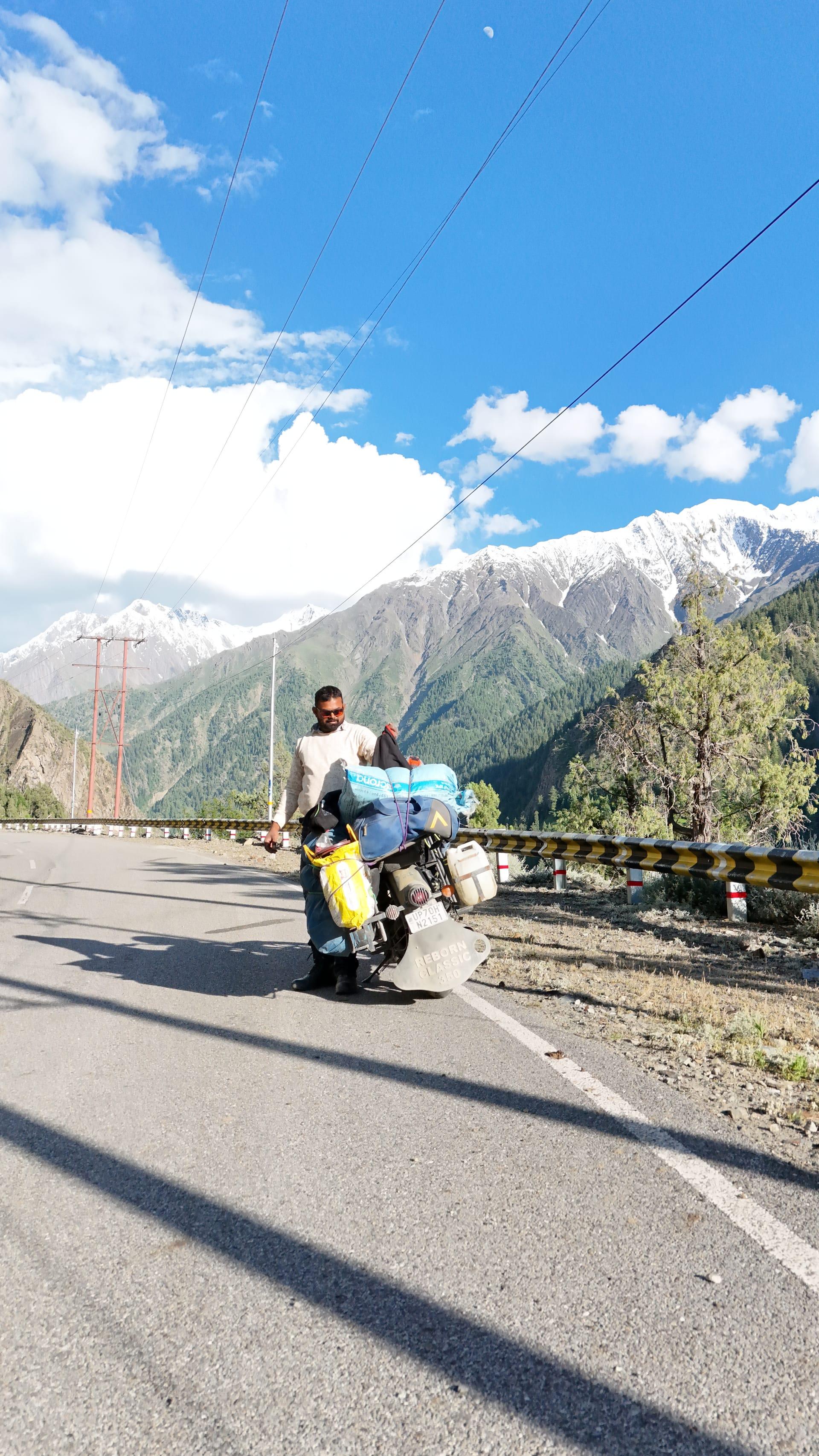 Loaded bike on the mountain road with snow peaks behind